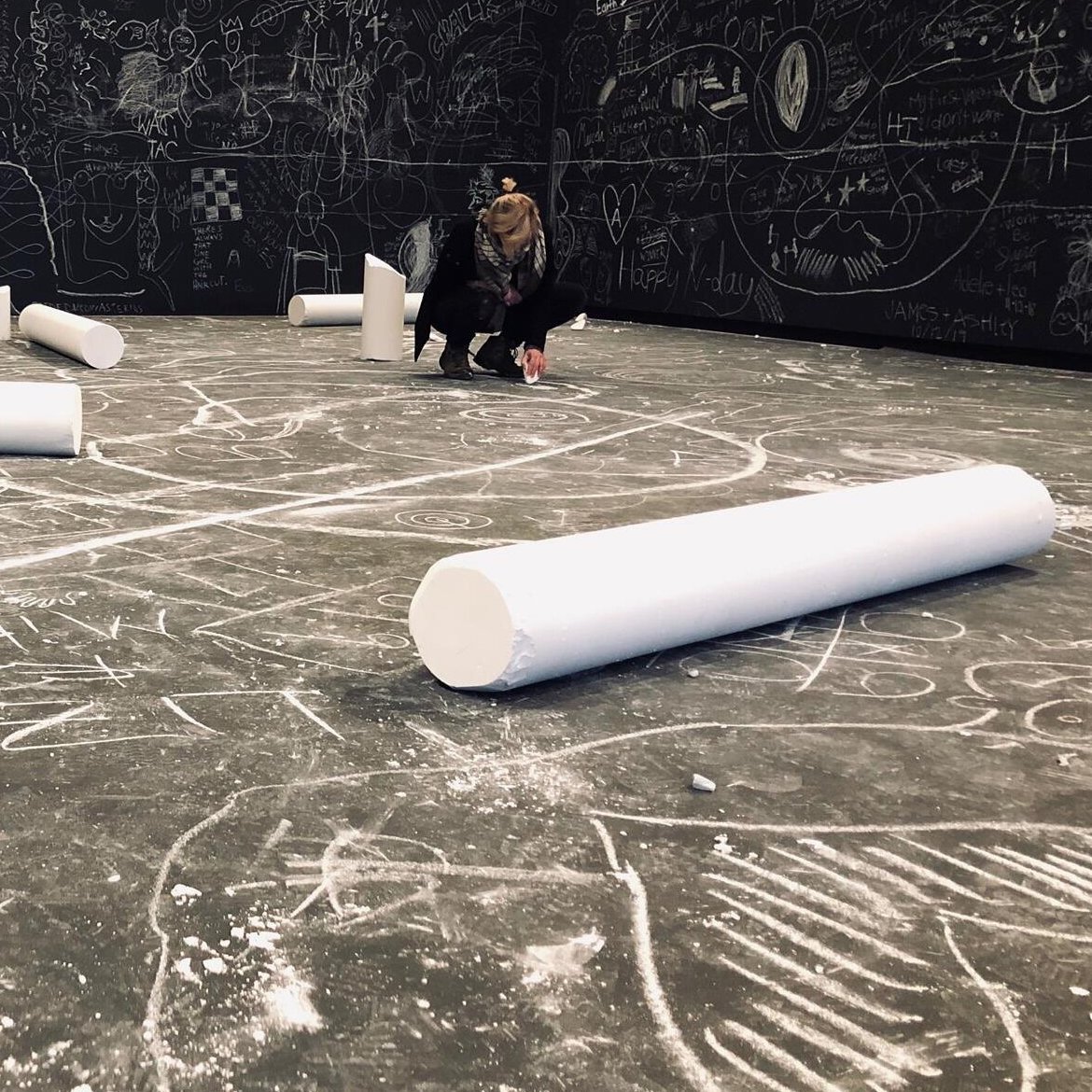 An image of Cat Saint-Croix in an interactive art exhibit drawing with large pieces of chalk.